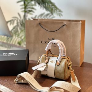 Coach's mini Boston bag is a new style in 2024. It has wide shoulder straps in milk tea color. The shoulder straps can be adjusted when carried cross-body. You can easily put down 10 bags without any pressure. The size is about 20*13*8.5